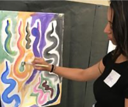 woman painting different color snakes on a canvas