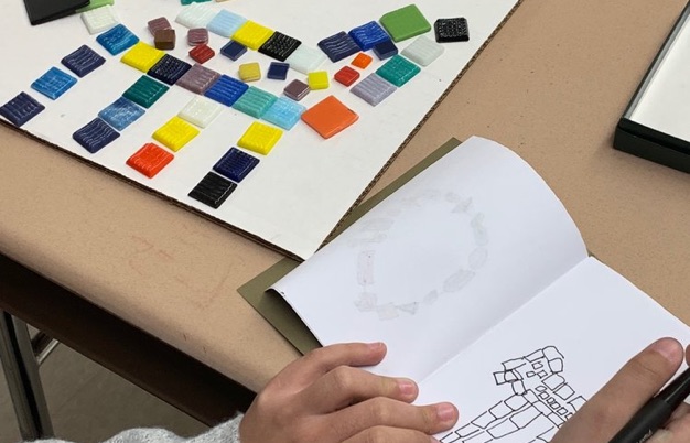 Child drawing mosaic design in notebook