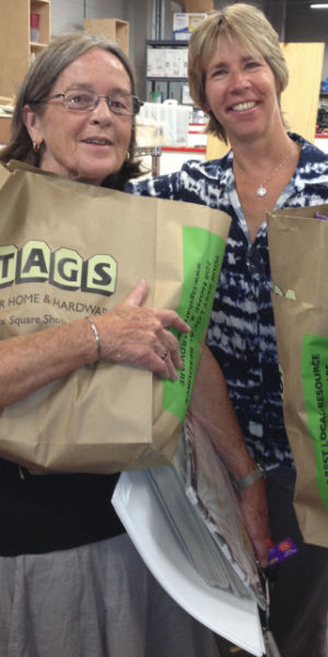 Two women holding paper bags of supplies