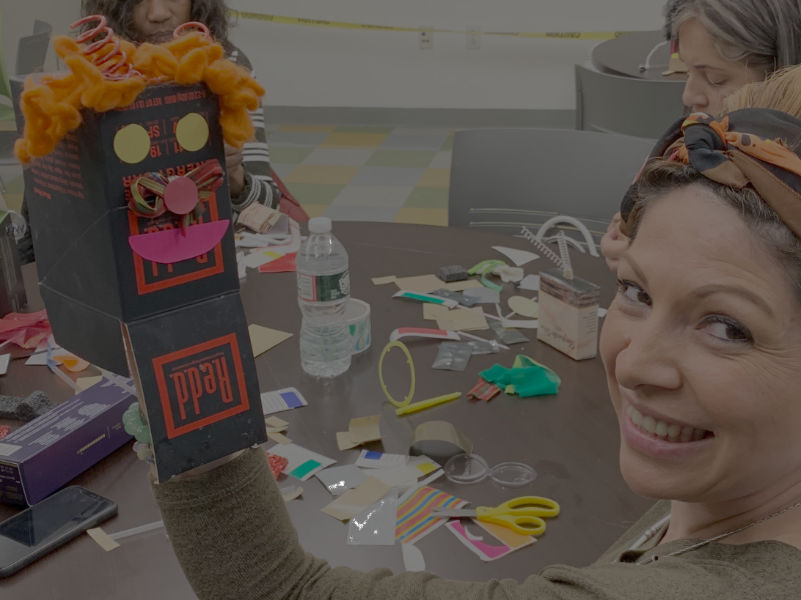 woman shows a puppet made from a box and craft supplies