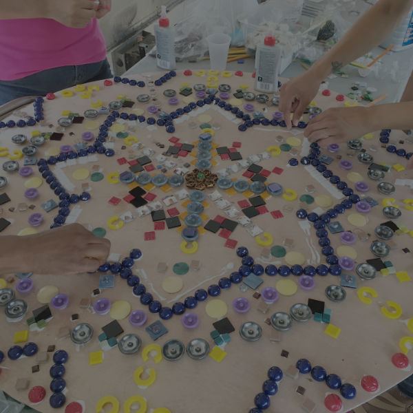 hands adding different color beads to a mandala design