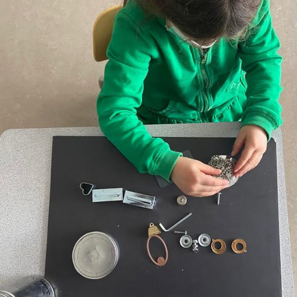 child playing with metal objects on a table